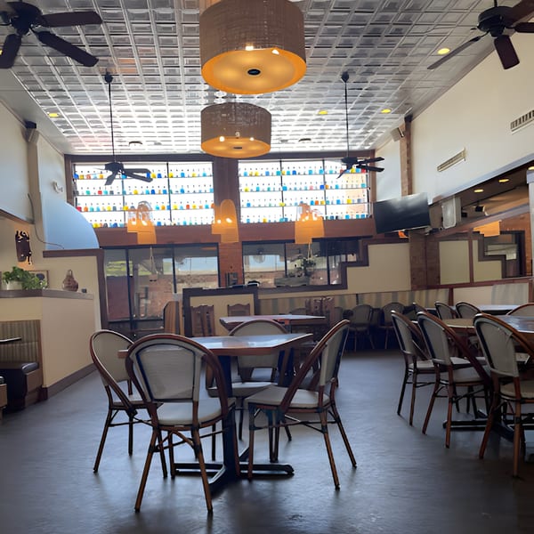 Interior of Fresco's Cocina Mexicana with tables, chairs, and colorful bottles lining a high window.