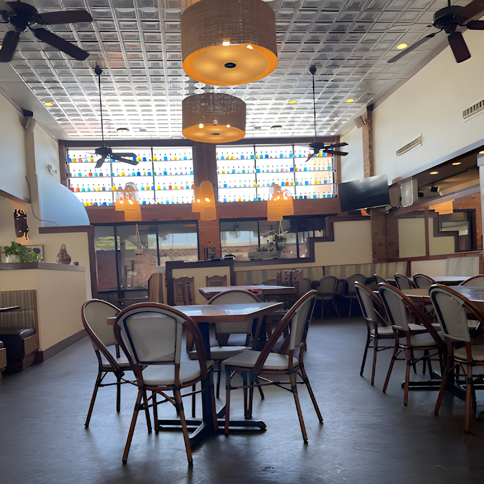 Interior of Fresco's Cocina Mexicana with tables, chairs, and colorful bottles lining a high window.