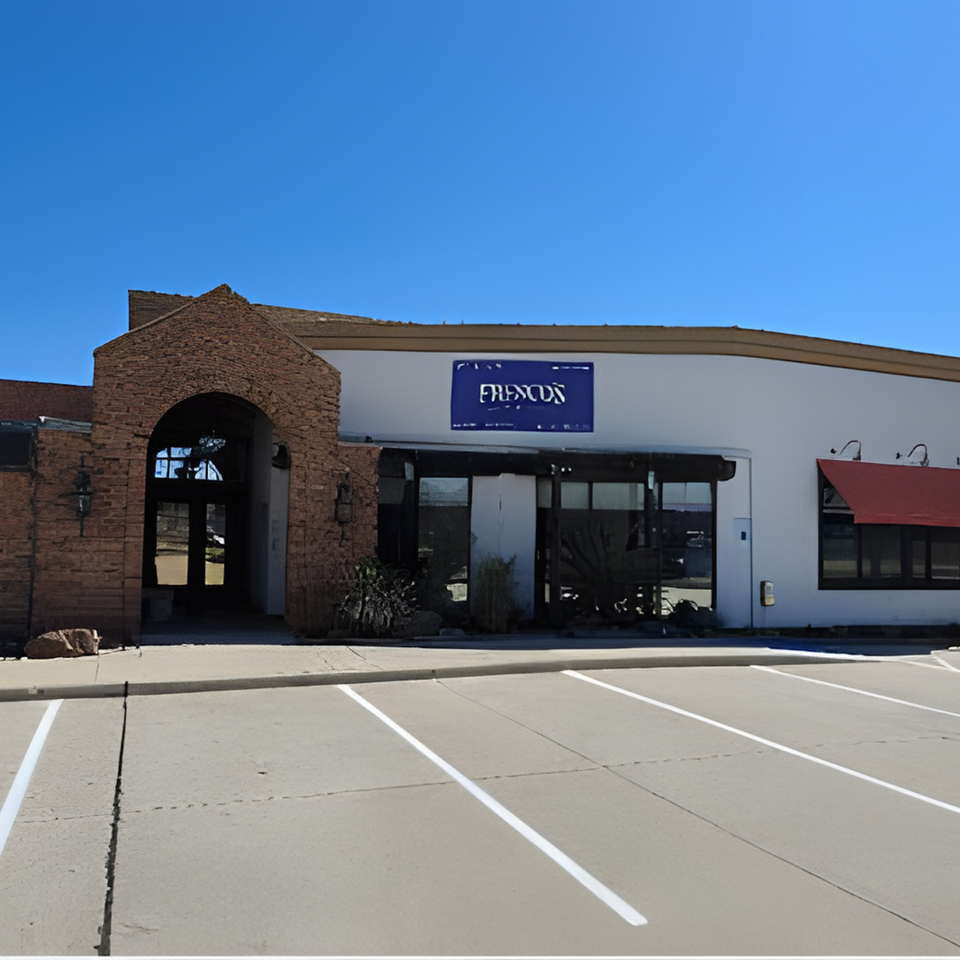 Exterior of Fresco's Cocina Mexicana, a white building with a brick archway entrance and red awning.